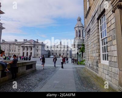 Die Studenten laufen am Campanile vorbei und durch den Innenhof des Library Square am Trinity College in Dublin, Irland. Stockfoto