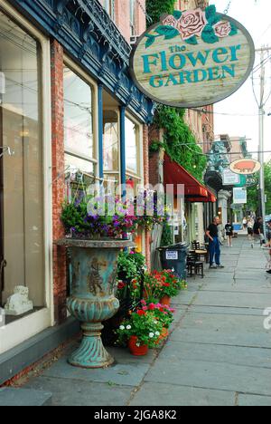 Auf den Gehwegen der Innenstadt von Saugerties, New York, zeigt ein Blumengeschäft und ein Souvenirladen ihr Handwerk. Die Stadt gilt als eine der coolsten Kleinstädte Stockfoto