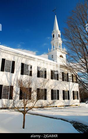 Eine klassische weiße Kirchturm New England Kirche steht in einer ländlichen Szene während eines Winterschnees ruft eine Weihnachtsfeiertage Szene Stockfoto