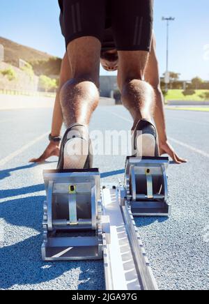 Füße des Athleten in Startposition auf einer Laufstrecke. Ein männlicher Track- und Feldläufer, der bereit ist, den Startblock zu verlassen, um seinen Sprint zu starten Stockfoto