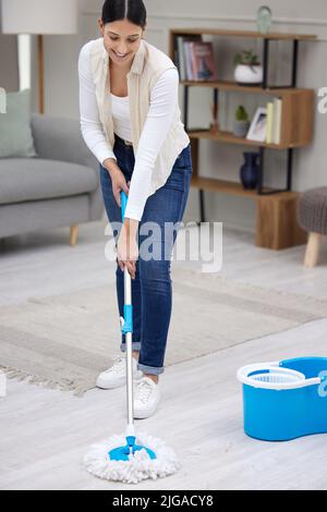 Saubere Böden zu sehen macht mich glücklich. Eine junge Frau, die zu Hause wischt. Stockfoto