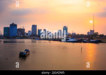 Ho Chi Minhs Panoramablick über den Saigon River. Dramatische Beleuchtung der spektakuläre Sonnenuntergang wird durch ein Kanu beim Surfen auf dem Wasser bei einer schnelleren Ratte hervorgehoben Stockfoto