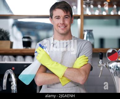 Fertig, fertig, lässt sauber. Ein junger Mann putzt in einem Café. Stockfoto