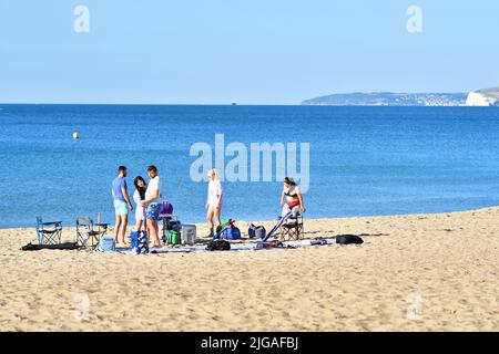 Boscombe, Bournemouth, Dorset, England, Großbritannien, 9.. Juli 2022, Wetter. Hitzewelle im Hochsommer. Am Samstagmorgen kommen die Leute vor 8 Uhr am Strand an. Die Temperaturen werden am Nachmittag bei Sonnenschein von Wand zu Wand das hohe 20s erreichen. Freunde, die sich am Strand aufmachen. Kredit: Paul Biggins/Alamy Live Nachrichten Stockfoto