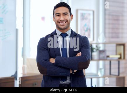 Ich möchte mit Ihnen Geschäfte machen. Ein hübscher junger Geschäftsmann, der mit gekreuzten Armen in seinem Büro steht. Stockfoto