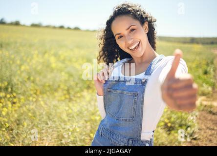 Dies ist ein toller Ort zu sein. Eine schöne junge Frau zeigt Daumen nach oben, während im Freien stehen. Stockfoto