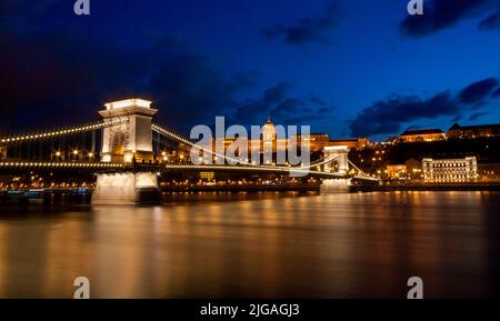 Königspalast oder die Budaer Burg und die Kettenbrücke nach Sonnenuntergang in Budapest in Ungarn. Stockfoto