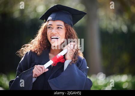 Träumen von spannenden Visionen ihrer Zukunft. Eine junge Frau hält am Abschlusstag ihr Diplom. Stockfoto