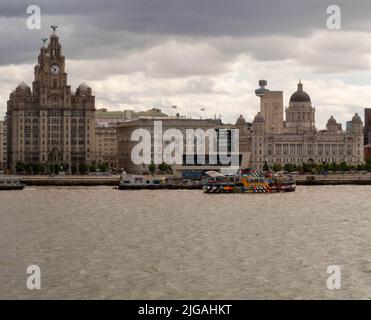 Liverpools ikonische Landschaft auf dem Fluss Mersey, einschließlich des Liver Building, des Liverpool Museum, einer farbenfrohen, lustigen Fähre. Stockfoto