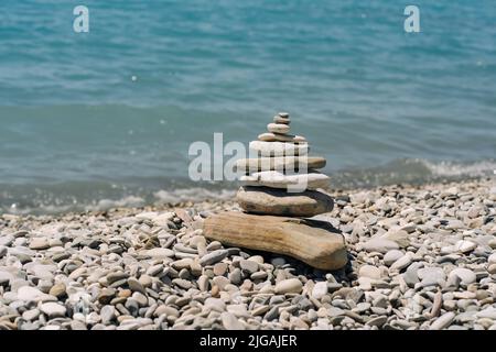 Ausgewogene Steine an einem Kieselstrand. Am Strand in einer Balancepyramide angeordnete Seesteine. Stockfoto