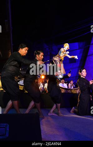 Thailändischer professioneller Puppenspieler oder Puppenspieler manipulieren das Spielen von schauspielenden antiken Puppenspielzeugen oder antiker Marionette auf der Bühne für die Show im Nachtfestival e Stockfoto