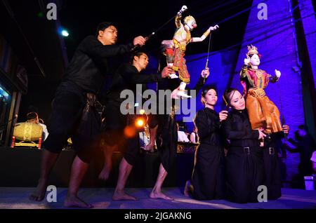 Thailändischer professioneller Puppenspieler oder Puppenspieler manipulieren das Spielen von schauspielenden antiken Puppenspielzeugen oder antiker Marionette auf der Bühne für die Show im Nachtfestival e Stockfoto