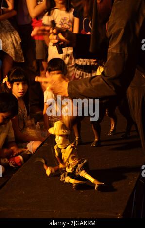 Thailändischer professioneller Puppenspieler oder Puppenspieler manipulieren das Spielen von schauspielenden antiken Puppenspielzeugen oder antiker Marionette auf der Bühne für die Show im Nachtfestival e Stockfoto