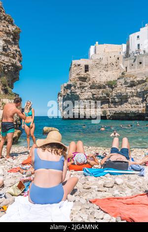 Schöne Aussicht auf Polignano a Mare mit weißen Steinhäusern, Klippen, Strand, blaues Meer und Touristen, Badegäste, umgeben von mediterraner Natur Stockfoto
