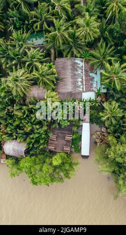 Luftaufnahme von oben nach unten auf dem Pier mit angedocktem Boot auf dem mekong Delta Fluss in Ben Tre Vietnam, umgeben von tropischen Dschungelbäumen Stockfoto