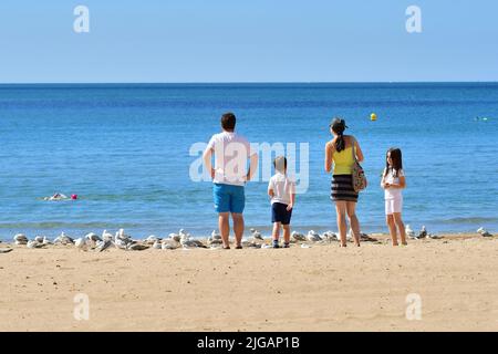 Familiengruppe steht am Strand mit Blick auf das Meer an heißen Sommertagen, Bournemouth, Dorset, England, Großbritannien, 9. Juli 2022, Hitzewelle. Stockfoto