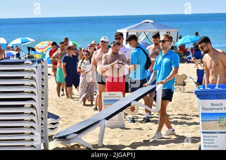 Leute, die sich am Bournemouth Beach in einer Hitzewelle um Liegen oder Liegestühle schlangen, Dorset, England, Großbritannien, 9. Juli 2022. Stockfoto