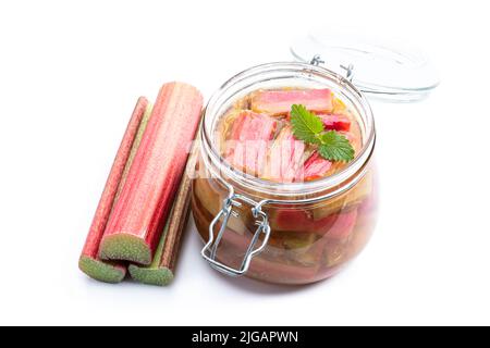 Hausgemachte Rhabarbermarmelade im Glas mit rohem Rhabarberstiel isoliert auf weiß Stockfoto