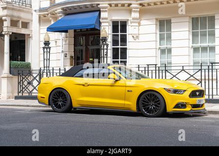 Gelbes Ford Mustang Muscle Car, das vor dem Grundstück in der Charles Street, Mayfair, London, Großbritannien, geparkt wurde. Exklusive Wohnimmobilien im teuren Mayfair Stockfoto