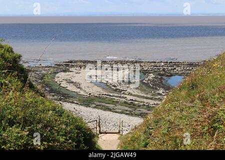 Stufen führen dow zum Kilve Beach in der Nähe von East Quantoxhead in Somerset, England. Gesteinsschichten aus der Jurazeit bilden entlang gesprungene Gehwege Stockfoto