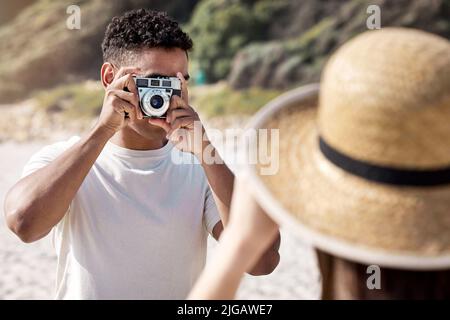 Ich könnte für immer Bilder von dir machen. Ein junger Mann, der Fotos von seiner Freundin am Strand machte. Stockfoto