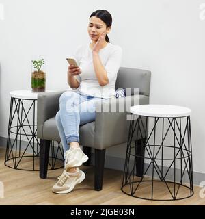 Die Zunge dreht sich immer zum schmerzenden Zahn. Eine junge Frau mit Zahnschmerzen sitzt in einem Wartezimmer beim Zahnarzt. Stockfoto