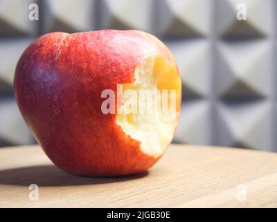 Ein gebissene Apfel auf einer Holzoberfläche. Makro „Reifer Apfel“. Stockfoto