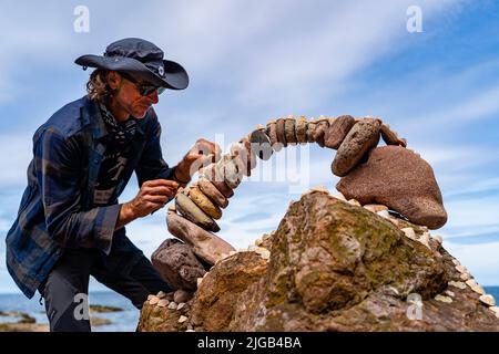 Dunbar, Schottland, Großbritannien. 9. Juli 2022. Tag eins der Stone Stacking Championships 11. am Eye Cave Beach in Dunbar in East Lothian. . Die Konkurrenz wird während des Wettkampfes im Bogenbau gezeigt. PIC; Pedro Duran und sein Steinbogen. Iain Masterton/Alamy Live News Stockfoto