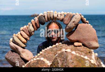 Dunbar, Schottland, Großbritannien. 9. Juli 2022. Tag eins der Stone Stacking Championships 11. am Eye Cave Beach in Dunbar in East Lothian. . Die Konkurrenz wird während des Wettkampfes im Bogenbau gezeigt. PIC; Pedro Duran und sein Steinbogen. Iain Masterton/Alamy Live News Stockfoto