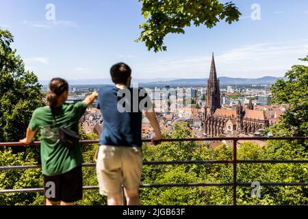 09. Juli 2022, Baden-Württemberg, Freiburg: Zwei Männer stehen auf dem Kanonenplatz auf dem Freiburger Schlossberg und blicken über die Stadt. Bei strahlendem Sonnenschein und Temperaturen um die 25 Grad ziehen sich viele Bewohner und Besucher der Stadt nach draußen. Foto: Philipp von Ditfurth/dpa Stockfoto