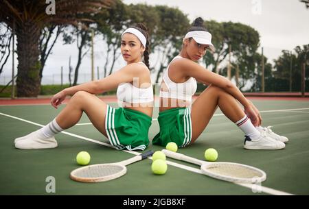 Wenn du gegen uns gehst, gehst du gegen die Besten. Zwei Tennisspieler, die sich auf einem Platz Rücken an Rücken lehnen. Stockfoto