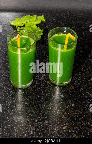 Grünes Getränk aus frischen Kräutern mit Chlorophyll in Gläsern auf einer schwarzen Tischoberfläche. Stockfoto