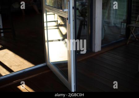 Tür zum Haus öffnen. Glastür im Erdgeschoss. Details zur Innenausstattung. Weiße Kunststofftür. Stockfoto