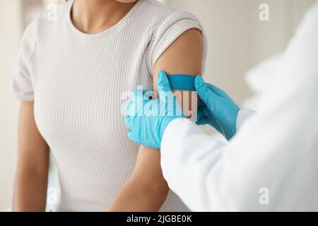 Eine nicht erkennbare Ärztin, die während einer Konsultation in der Klinik ein Pfandhilfsmittel einspritzt, nachdem sie ihre Patientin injiziert hat. Stockfoto