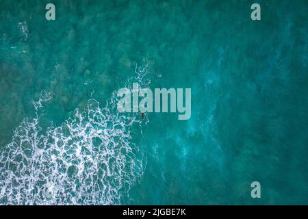 Luftaufnahme von Surfern im Meerwasser, die eine Welle fangen Stockfoto