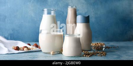 Glaswaren verschiedener veganer Milch auf blauem Hintergrund Stockfoto