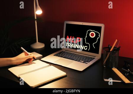 Frau mit Notebook und Laptop am Tisch am Abend. NLP-Schulung Stockfoto