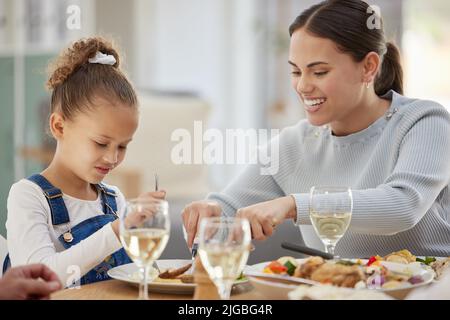 Mama bekommt die Größen mich freundlich. Eine Mutter schneidet ihre kleinen Mädchen Essen für sie. Stockfoto