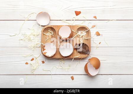 Komposition mit Eierschalen-Halter auf hellem Holzhintergrund Stockfoto