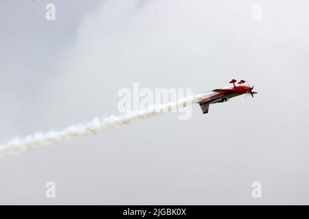 Gera, Deutschland. 09.. Juli 2022. Florian Berger fliegt bei den Deutschen Aerobatic Meisterschaften als neuer Deutscher Aerobatic Champion mit einer Kunstflugmaschine Extra 330 und zeigt Kunstflug-Figuren in der Luft. Dabei sprüht er weißen Kunstflugnebel. 30 Teilnehmer aus Deutschland und Luxemburg haben nach Angaben des Veranstalters an der Meisterschaft teilgenommen. (An dpa 'Deutscher Kunstflugmeister kommt aus Bayern') Quelle: Bodo Schackow/dpa/Alamy Live News Stockfoto