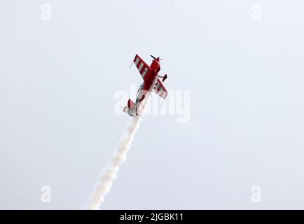 Gera, Deutschland. 09.. Juli 2022. Florian Berger fliegt bei den Deutschen Aerobatic Meisterschaften als neuer Deutscher Aerobatic Champion mit einer Kunstflugmaschine Extra 330 und zeigt Kunstflug-Figuren in der Luft. Dabei sprüht er weißen Kunstflugnebel. 30 Teilnehmer aus Deutschland und Luxemburg haben nach Angaben des Veranstalters an der Meisterschaft teilgenommen. (An dpa 'Deutscher Kunstflugmeister kommt aus Bayern') Quelle: Bodo Schackow/dpa/Alamy Live News Stockfoto