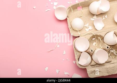 Papphalter mit zerbrochenen Eierschalen auf rosa Hintergrund, Nahaufnahme Stockfoto