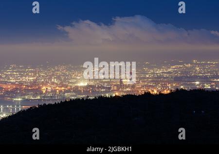 Blauer Himmel und Wolken über den Lichtern der weitläufigen Stadt in der Nacht Stockfoto