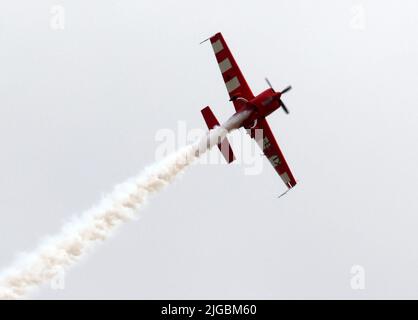 Gera, Deutschland. 09.. Juli 2022. Florian Berger fliegt bei den Deutschen Aerobatic Meisterschaften als neuer Deutscher Aerobatic Champion mit einer Kunstflugmaschine Extra 330 und zeigt Kunstflug-Figuren in der Luft. Dabei sprüht er weißen Kunstflugnebel. 30 Teilnehmer aus Deutschland und Luxemburg haben nach Angaben des Veranstalters an der Meisterschaft teilgenommen. (An dpa 'Deutscher Kunstflugmeister kommt aus Bayern') Quelle: Bodo Schackow/dpa/Alamy Live News Stockfoto