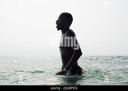Junger schwarzer Fußballspieler, der am frühen Morgen in Barcelona Aqua-Workout im Meer macht Stockfoto