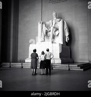 1960s, historisch, eine Familie, die in einem neoklassizistischen Tempel in Washington, DC, USA, steht und eine Statue und ein Denkmal für den US-Präsidenten Abraham Lincoln aus dem Jahr 16. sieht. Die 1922 eröffnete Statue wurde von Daniel Chester French entworfen. Stockfoto