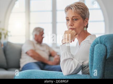 Hat sich das alles gelohnt? Ein älteres Paar, das nach einem Streit traurig und aufgeregt in ihrem Wohnzimmer sitzt. Stockfoto