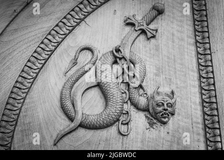 Symbol der Teufelsschlange. Fantasy magische Kreatur an einer alten Tür, 12th Jahrhundert Abtei, Italien. Stockfoto