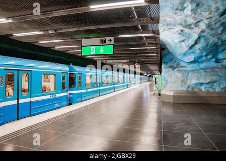 Passagiere, die im blauen Zug unterwegs waren, kamen am beleuchteten Bahnhof Stadion an Stockfoto