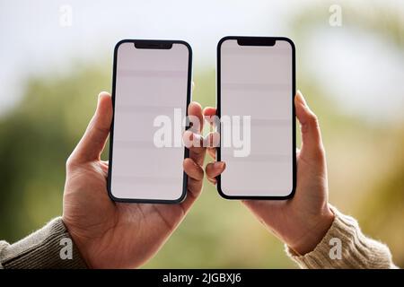 Es ist ein Spiel im Himmel gemacht. Ein unverkennbares Paar hält ihre Handys nebeneinander. Stockfoto